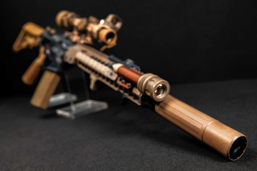 Gold gun with suppressor attached.